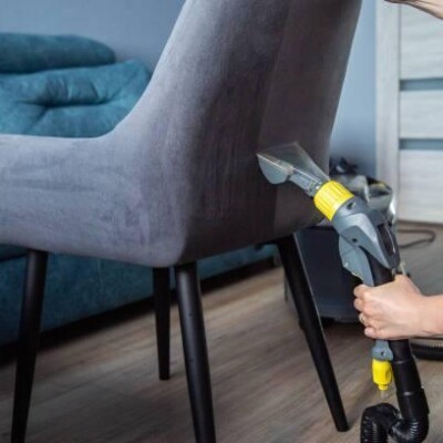 Dry cleaning services, washing and cleaning gray fabric chairs with a washing vacuum cleaner.